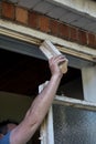 Workman using his hand and arm to remove old wooden window frame