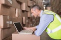 Workman using laptop at warehouse