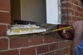 Workman using a saw and crowbar to remove an old wooden window frame