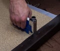 Workman using staples and stapler to upholster paricle board.