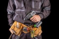 Workman in work clothes and tool belt. Production worker with a drill in his hand Royalty Free Stock Photo