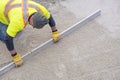 Workman in Yellow Safety Vest Using a 10 Foot Level Tool Over a Patio Area