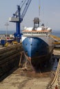 Workmen cleaning the hull of a merchant ship in the dry dock of a shipyard in Gibraltar. Cranes, heavy tools, ships Royalty Free Stock Photo