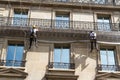 Workmen on ropes on old residential building front, Paris. Royalty Free Stock Photo