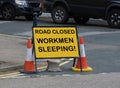 Workmen sleeping road closed sign warning public notice