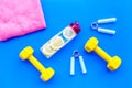 Workout with bars, bottle of water, towel and wrist builder blue background top view