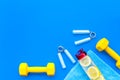 Workout with bars, bottle of water and wrist builder blue background top view mockup