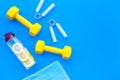 Workout with bars, bottle of water and wrist builder blue background top view mockup
