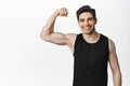 Workout and gym concept. Smiling handsome man showing his muscles after sport exercises, flexing biceps with pleased