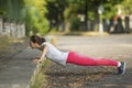 Workout in a Park. Young sporty woman doing push-ups in park in sunshine on beautiful summer day. Royalty Free Stock Photo