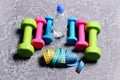 Barbells, colorful tape measures and water bottle placed in pattern