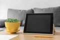 Workplace accessories for working online. Tablet, pen, flower pot with fresh microgreen basil on table, sofa background Royalty Free Stock Photo