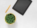 Workplace accessories for working online. Tablet, pen, flower pot with fresh microgreen basil on a white background Royalty Free Stock Photo