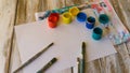 workplace of the artist: watercolor paints, paint brushes, sheets of white paper, color palette and unfinished painting Royalty Free Stock Photo
