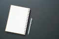 Workplace background concept with empty white spiral notebook and grey pen placed on black background. Royalty Free Stock Photo