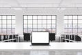 A workplace in a bright modern loft open space office. A working desk is equipped with a modern laptop with white copy space in th Royalty Free Stock Photo