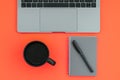 Workplace with a colored background. Laptop, a cup of coffee, a notepad with a pen isolated on a red background Royalty Free Stock Photo