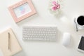 Workplace with computer keyboard and bouquet of beautiful pink flowers on white table, top view Royalty Free Stock Photo