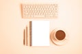 Workplace with computer keyboard, notepad, pen, pencil and cup of coffee or cocoa on peachy background. Top view, flat Royalty Free Stock Photo