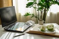 A workplace with a computer, an open book, an apple, a medical mask and a cup of coffee