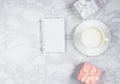 Workplace with a cup of coffee, black note and gift boxes on a marble table. Top view, flat lay, copy space