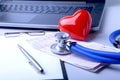 Workplace of doctor with laptop, stethoscope, red heart and RX prescription on white table. top view. Royalty Free Stock Photo