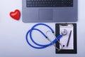 Workplace of doctor with laptop, stethoscope, RX prescription, glasses and red heart and notebook on white table. top Royalty Free Stock Photo