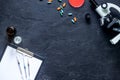 Workplace of doctor. Microscope, syringe, Petri dish, pad and pills on grey stone background top view copyspace