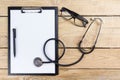 Workplace of a doctor. Pen, stethoscope, clipboard on wooden desk background. Top view Royalty Free Stock Photo