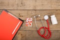 Workplace of doctor. Red stethoscope, clipboard and pills on wooden desk Royalty Free Stock Photo