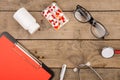 Workplace of doctor. Stethoscope, clipboard, glasses and pills on wooden desk Royalty Free Stock Photo