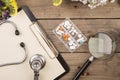 Workplace of a doctor. Stethoscope, clipboard, pills and other stuff on wooden desk Royalty Free Stock Photo