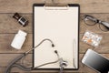 Workplace of a doctor. Stethoscope, clipboard, pills, smartphone and other stuff on wooden desk Royalty Free Stock Photo