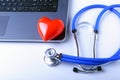 Workplace of doctor with stethoscope, red heart, laptop, rx prescription and notebook on white table. top view.