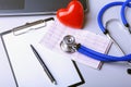 Workplace of doctor with stethoscope, red heart, laptop, rx prescription and notebook on white table. top view. Royalty Free Stock Photo