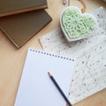 Empty notepad, candle shape of heart and books on wooden table.