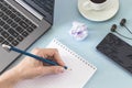 Workplace. Female hands with a notebook and pencil laptop smartphone headphones cup of coffee. Royalty Free Stock Photo