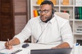 Workplace of freelancer. African-American man works at home office using computer, headset and other devices. Employee Royalty Free Stock Photo