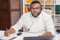 Workplace of freelancer. African-American man works at home office using computer, headset and other devices. Employee Royalty Free Stock Photo