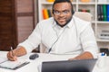 Workplace of freelancer. African-American man works at home office using computer, headset and other devices. Employee Royalty Free Stock Photo