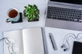 Workplace at home: Laptop, notebook with pen, smartphone and cup of tea on white desktop Royalty Free Stock Photo