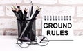 A workplace in the house with glasses, pencils in a stand and a notebook with text GROUND RULES on a brick wall background. Home Royalty Free Stock Photo