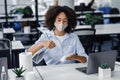Workplace hygiene to protect health against coronavirus. African american woman in mask use spray and paper towels to Royalty Free Stock Photo