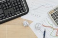 Workplace with keyboard, graph, calculator, and pan on wood table Royalty Free Stock Photo