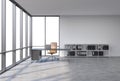 A workplace in a modern corner panoramic office with copy space in the windows. A black desk with a laptop, brown leather chair an