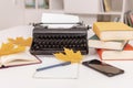 Workplace of modern writer with old typewriter, books, notebook and pen, telephone. Autumn mood. Royalty Free Stock Photo