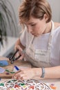 Workplace of the mosaic master: women`s hands holding tool for mosaic details in the process of making a mosaic Royalty Free Stock Photo