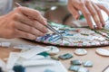 Workplace of the mosaic master: women`s hands holding tool for mosaic details in the process of making a mosaic