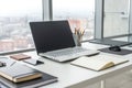 Workplace with notebook laptop Comfortable work table in office windows and city view.