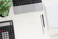 Workplace in office - desk with laptop, calculator, stack of papers, notebook, a pen and a green plant. Royalty Free Stock Photo